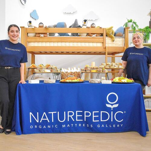 The reception table set with food, with two Naturepedic staff members standing on either side