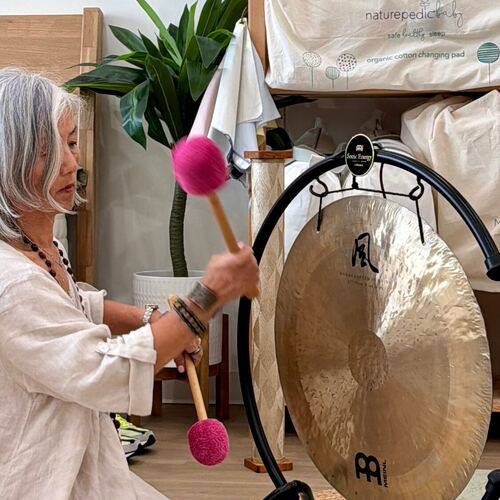 Mi Sun playing the gong with a felt mallet